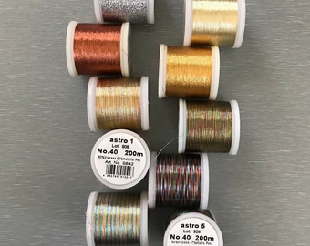 May include: Eight spools of metallic thread in various colors, including silver, gold, copper, and multi-colored. Each spool is labeled with "astro" and a number, along with the text "No.40 200m".