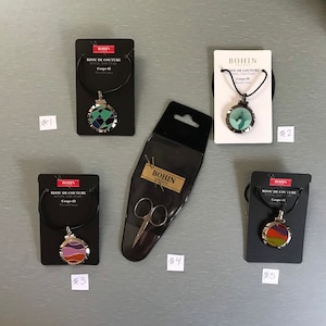 May include: Five packages containing sewing supplies. The packages are labeled with the brand name "BOHIN" and the text "BIJOU DE COUTURE". The packages contain a pair of small scissors, and three different thread cutters with colorful designs.