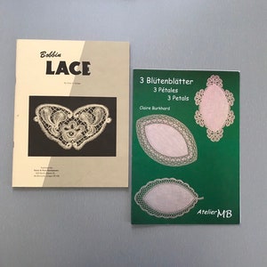 May include: Two books on bobbin lace. The book on the left is titled "Bobbin Lace" and features a heart-shaped lace design. The book on the right is titled "3 Blütenblätter 3 Pétales 3 Petals" and features three oval-shaped lace designs. The book on the right also has the text "Claire Burkhard" and "Atelier MB".