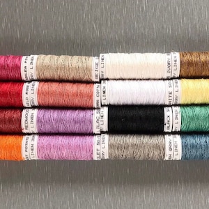May include: A collection of 12 spools of linen thread in various colors, including red, orange, pink, purple, brown, yellow, green, blue, black, white, and beige. Each spool is labeled with the color name and the brand "LINDRY".