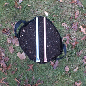 May include: A black fabric grow bag filled with dark brown soil. Two metal rods, one silver and one copper, are inserted into the soil.