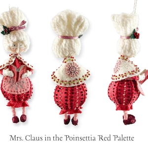 K&ouml;nnte beinhalten: Ein handgefertigter Weihnachtsbaumschmuck aus Filz, der Frau Claus in einem rot-wei&szlig;en Kleid im Poinsettien-Stil zeigt. Sie h&auml;lt ein Buch in der Hand und tr&auml;gt einen wei&szlig;en H&auml;kelhut mit einem rosa Band.