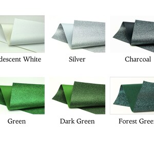 Op de afbeelding: Zes staaltjes glitterstof in verschillende kleuren: iriserend wit, zilver, antraciet, groen, donkergroen en bosgroen.