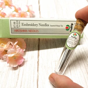 Puede incluir: Un tubo de vidrio lleno de agujas de bordado finas surtidas en tama&ntilde;os 7, 8, 9 y 10. El tubo est&aacute; etiquetado como "Tulip Embroidery Needles Assorted Thin".