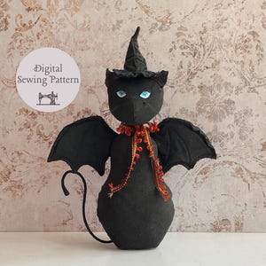 May include: A black cat-shaped Halloween decoration with bat wings, a witch's hat, and blue eyes. The cat wears an orange and gold beaded necklace. The image includes a circular graphic that reads "Digital Sewing Pattern".