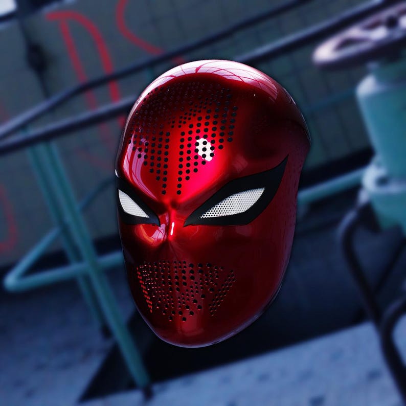 Op de afbeelding: Een glanzend rood full-face masker met een geperforeerd patroon. Het masker heeft witte oogopeningen en een zwarte omtrek. Het masker is waarschijnlijk voor cosplay of kostuums.