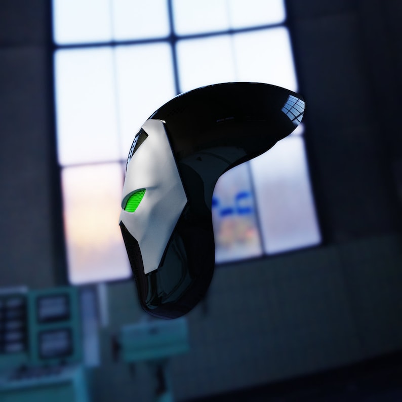 May include: A black and white mask with a green eye. The mask is made of plastic and has a smooth surface.