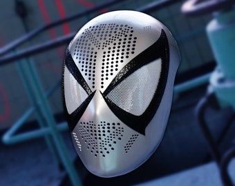 Könnte beinhalten: Eine silberne und schwarze Spider-Man-Maske mit einem Netz-Augen-Design. Die Maske hat eine strukturierte Oberfläche mit kleinen Löchern.