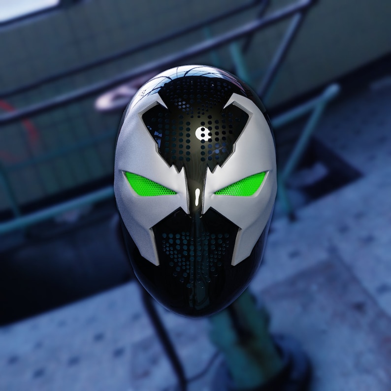 May include: A black and white mask with green eyes. The mask has a textured surface and a design that resembles a skull.