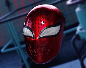 Könnte beinhalten: Eine rote und schwarze Spider-Man-Maske mit einem Netz-Augen-Design. Die Maske hat eine strukturierte Oberfläche mit kleinen Löchern.