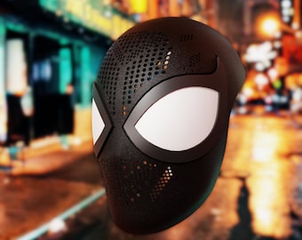 May include: Black and white spider-man mask with a textured surface and a small hole pattern. The mask has a white eye area.
