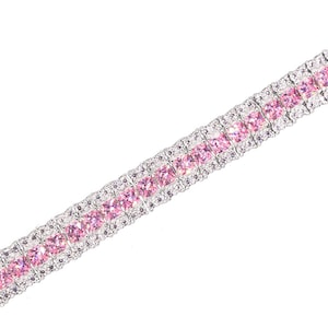 Può includere: Un braccialetto d'argento con una fila di strass quadrati rosa e trasparenti.