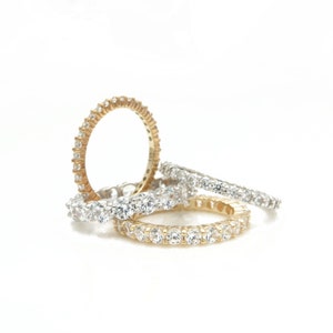 Op de afbeelding: Drie eeuwigheidsringen met ronde briljant geslepen diamanten gezet in een pavé setting. De bovenste ring is goud, de middelste ring is zilver en de onderste ring is goud.