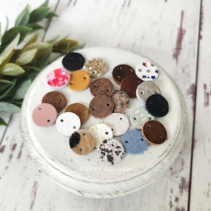 May include: Assortment of small, round leather patches in various colors and patterns, including cowhide, stars, and polka dots. The patches have two holes each and are displayed on a white plate with the text "POPPY SQUASH".