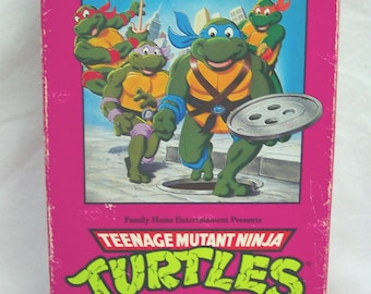 May include: A vintage VHS tape for "Teenage Mutant Ninja Turtles: April Foolish" from Burger King's Kids Club. The pink box features the Turtles and the Burger King Kids Club logo.