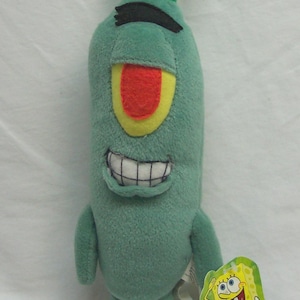 May include: A plush toy of Plankton from the animated series Spongebob Squarepants. The green, cylindrical character has a large, red and yellow eye, a wide grin, and two green antennae with black bands. A small tag featuring Spongebob is attached.