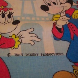 Puede incluir: Un personaje de dibujos animados rojo y amarillo con un lazo en la cabeza y un vestido rojo y amarillo. Est&aacute; de pie junto a un personaje de dibujos animados azul y blanco con un sombrero amarillo y una faja roja. El fondo es azul y blanco con una Torre Eiffel blanca.