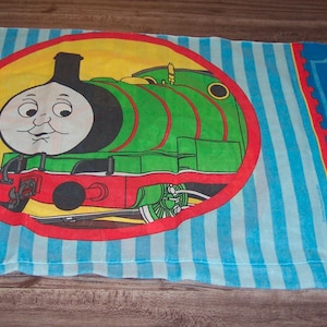 May include: A white ceramic mug with a black handle and the text "But First, Coffee" in a handwritten style. The mug is on a white surface. The mug is approximately 4 inches tall.