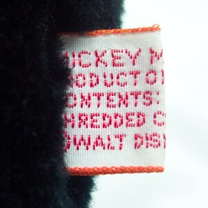 May include: White tag with red text that reads "Mickey Mouse Product Contains Shredded Contents, Small Parts".