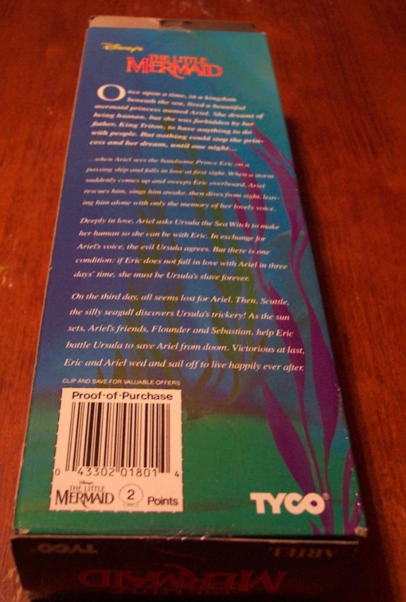 May include: A VHS tape case for the Disney movie The Little Mermaid. The case is blue and green with a picture of Ariel, the mermaid princess, on the front. The back of the case has a description of the movie and a proof-of-purchase barcode. The case also has the TYCO logo.