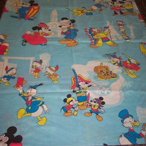 Puede incluir: Una tela azul y blanca con un patr&oacute;n repetido de personajes de Mickey Mouse y Donald Duck. Los personajes est&aacute;n vestidos con varios disfraces, incluyendo un pirata, un vaquero y un chef. La tela es perfecta para la habitaci&oacute;n de un ni&ntilde;o o una sala de juegos.