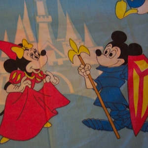 Puede incluir: Un personaje de dibujos animados rojo y amarillo con un escudo y una lanza se encuentra junto a un personaje de dibujos animados rojo y amarillo que lleva un vestido rojo y una capa amarilla. Los personajes est&aacute;n frente a un castillo azul y blanco.