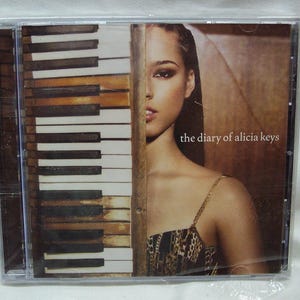 May include: A CD case with a photo of Alicia Keys on the front. The background is a close-up of a piano keyboard. The text "the diary of alicia keys" is printed on the front of the case.