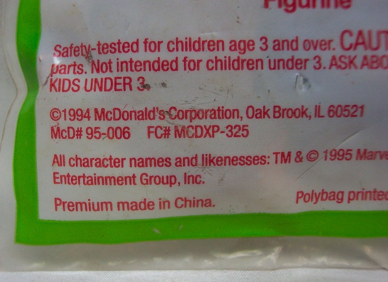 Pu&ograve; includere: Un sacchetto di plastica bianco con testo rosso e verde. Il testo recita: "Safety-tested for children age 3 and over. CAUT parts. Not intended for children under 3. ASK ABO KIDS UNDER 3 &copy;1994 McDonald's Corporation, Oak Brook, IL 60521 McD# 95-006 FC# MCDXP-325 All character names and likenesses: TM & &copy; 1995 Marve Entertainment Group, Inc. Premium made in China. Polybag printed"