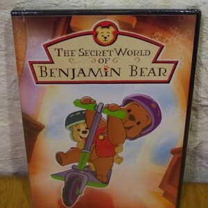 May include: DVD case for "The Secret World of Benjamin Bear." The cover features an illustration of a brown bear riding a green scooter, wearing a purple helmet. The title is in red and gold lettering.