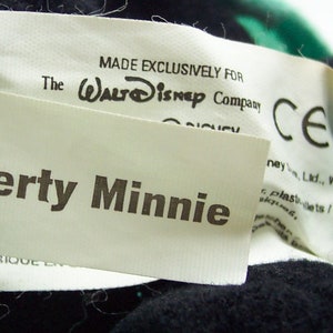 Peut inclure: &Eacute;tiquette blanche avec texte noir qui dit "MADE EXCLUSIVELY FOR The WALT Disney Company CE Liberty Minnie FABRIQUE EN".