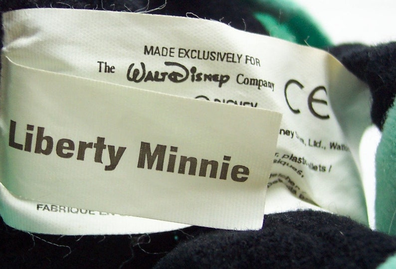 Peut inclure: &Eacute;tiquette blanche avec texte noir qui dit "MADE EXCLUSIVELY FOR The WALT Disney Company CE Liberty Minnie FABRIQUE EN".