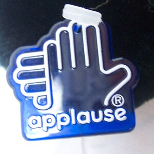 May include: A blue plastic tag with a white handprint and the word "applause" in white letters. The tag has a registered trademark symbol.