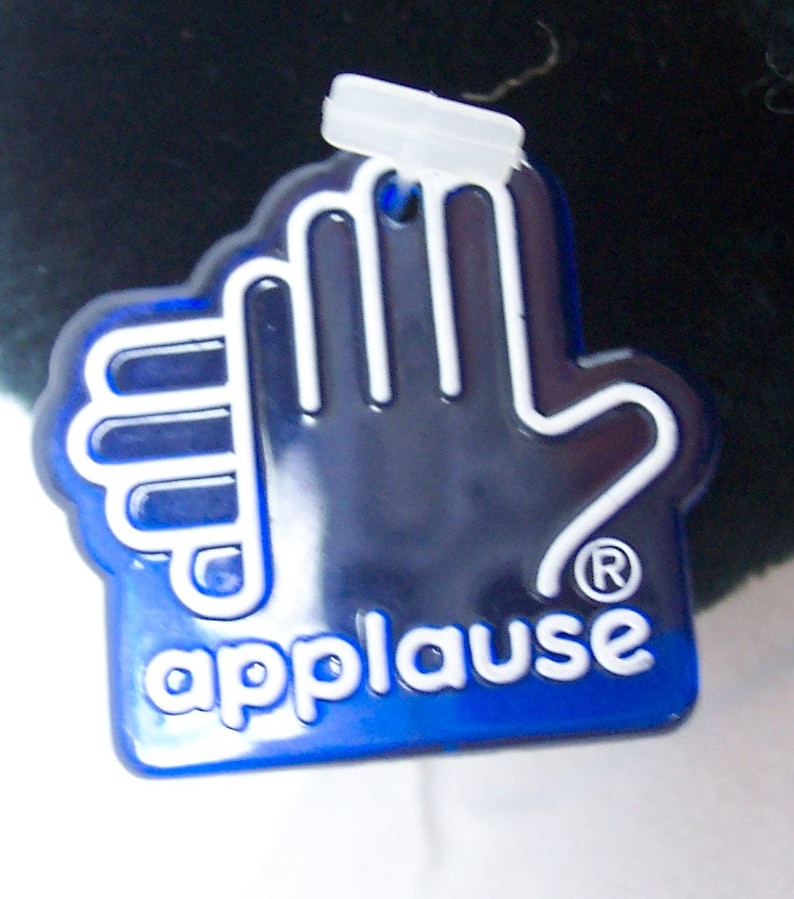 May include: A blue plastic tag with a white handprint and the word "applause" in white letters. The tag has a registered trademark symbol.