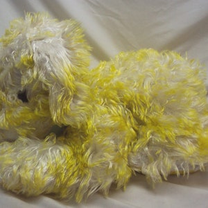 Può includere: Un cane di peluche con pelliccia bianca e gialla. Il cane è sdraiato sul fianco con la testa appoggiata sulle zampe.