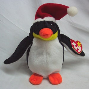 May include: A white and black penguin plush toy wearing a red Santa hat with a white pom-pom. The penguin has an orange beak and yellow eyes. The toy has a red Ty tag attached to its right wing.
