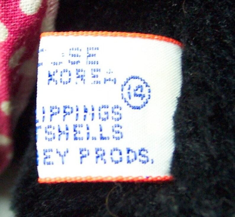 May include: White tag with blue text that reads "Lippings Shells Ney Prods." and a blue circle with the number "12" inside. The tag has an orange border.