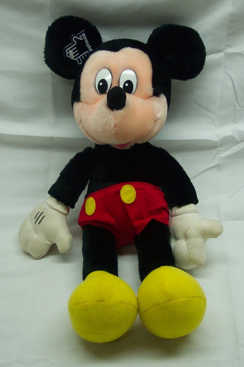 May include: A plush black Mickey Mouse toy with yellow shoes and red shorts with yellow buttons. The toy has a white tag on its ear that says "Applause".