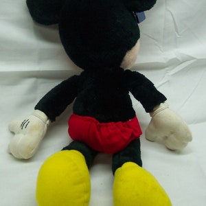 May include: A plush Mickey Mouse toy with black fur, yellow shoes, and a red and white shorts.