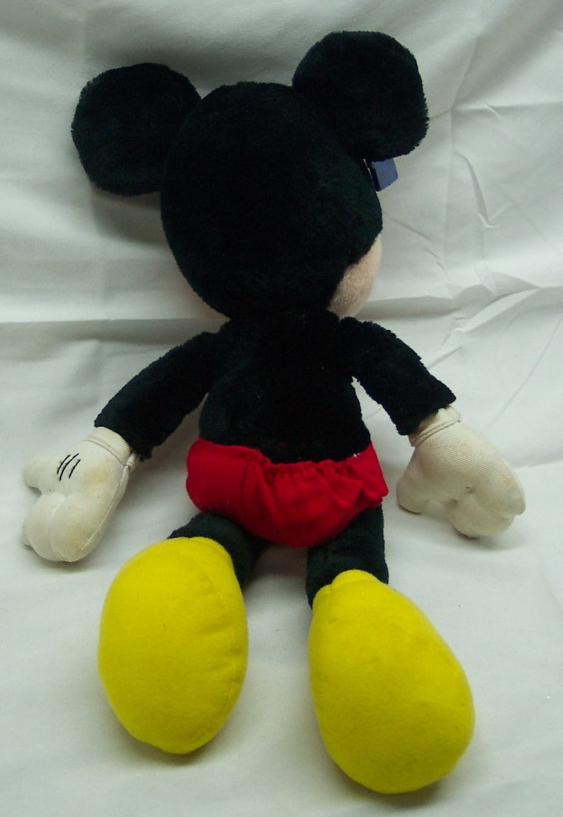 May include: A plush Mickey Mouse toy with black fur, yellow shoes, and a red and white shorts.