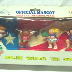 May include: A set of four Cabbage Patch Kids Olympikids figurines in a plastic package. The figurines are dressed in different sports uniforms and are holding sports equipment. The package is decorated with the American flag and the words "Official Mascot 1994 U.S. Olympic Team".