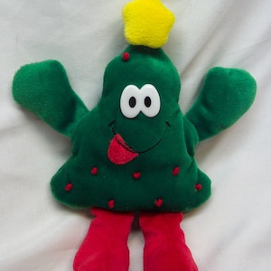 May include: A green plush Christmas tree toy with a yellow star on top. The tree has a smiling face with a red tongue sticking out and red legs.