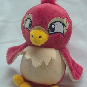 May include: A plush bird toy with a red body, wings, and head tuft. It has a yellow beak and feet, with large eyes outlined in gold. The bird has a cream-colored chest and a white, scalloped collar.