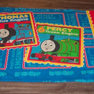 May include: A blue pillowcase featuring Thomas the Blue Engine and Percy the Green Engine. The pillowcase has a red border and a blue background with train graphics and text that reads "Really Reliable" and "Full Steam Ahead."