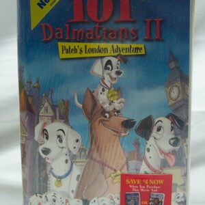 May include: A VHS tape cover for the movie "101 Dalmatians II: Patch's London Adventure". The cover features a blue background with a large image of the dalmatian dog Patch, along with other dalmatian dogs and a brown dog. The text "All New!" is in a yellow box in the top left corner. The text "Save $4 Now" is in a red box in the bottom right corner.