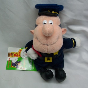 May include: A plush toy of a police officer with a blue uniform, a black hat with a gold trim, and a red and white striped scarf. The toy is holding a red object in its right hand.