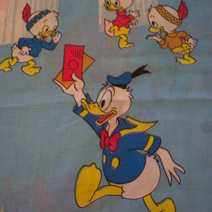 Puede incluir: Una ilustraci&oacute;n vintage de Donald Duck con un traje de marinero y sosteniendo un mapa rojo y blanco. Otros tres patos llevan tocados de nativos americanos y est&aacute;n en el fondo. El fondo es azul con un borde blanco.