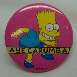 May include: A pink round button with a cartoon image of Bart Simpson from The Simpsons. Bart is wearing a blue shirt and is running with the text "Aye Carumba!" on a green banner.
