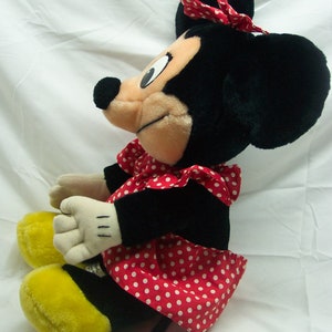 Peut inclure: Un jouet en peluche Minnie Mouse noir et blanc portant une robe &agrave; pois rouges et blancs avec un n&oelig;ud rouge sur la t&ecirc;te.