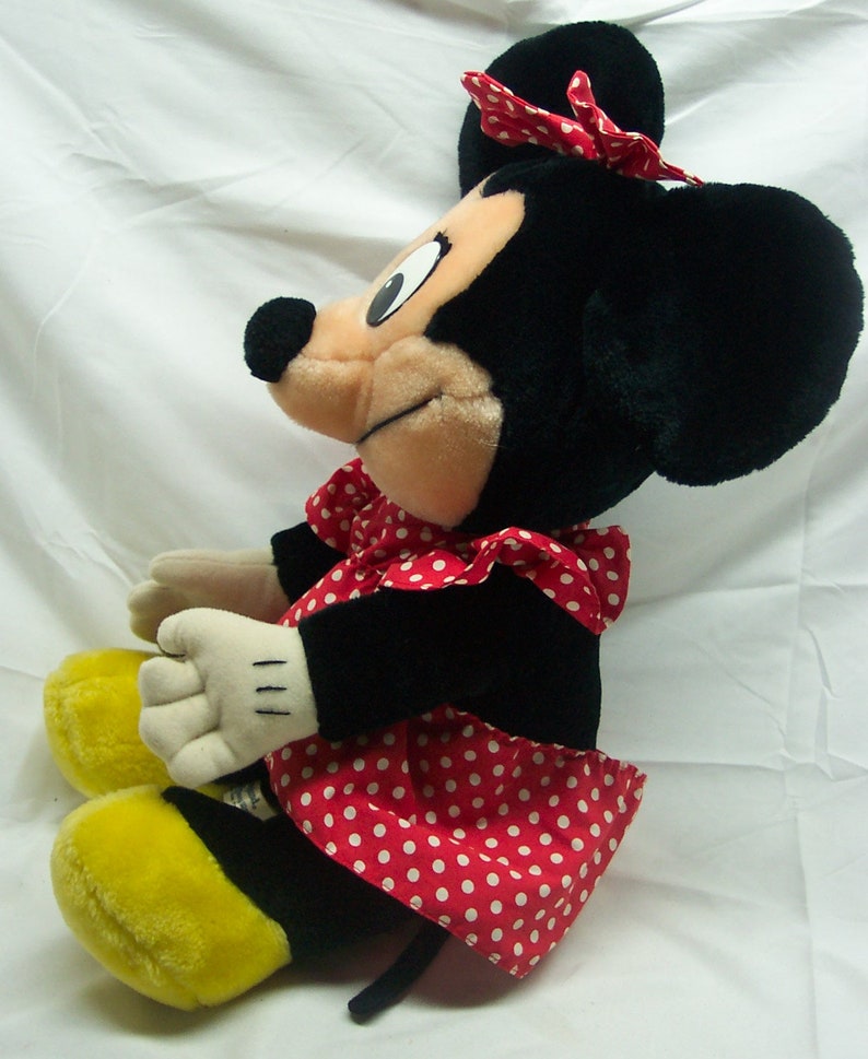 Peut inclure: Un jouet en peluche Minnie Mouse noir et blanc portant une robe &agrave; pois rouges et blancs avec un n&oelig;ud rouge sur la t&ecirc;te.