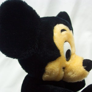 May include: A black and yellow plush Mickey Mouse toy with large black ears and a big smile.